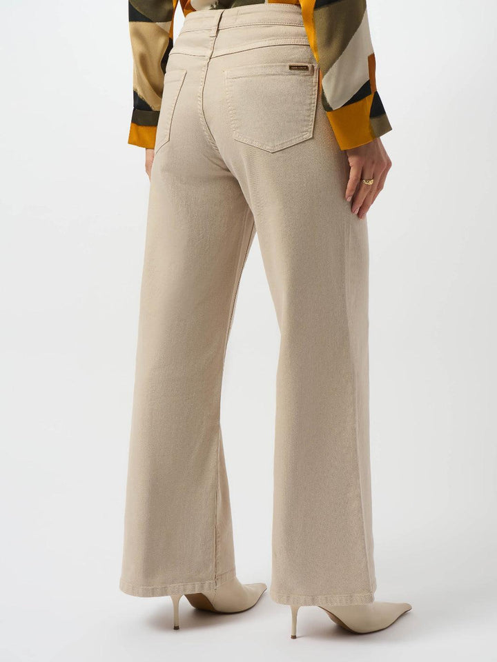 Beige flared pants worn with a colorful striped shirt on a white background