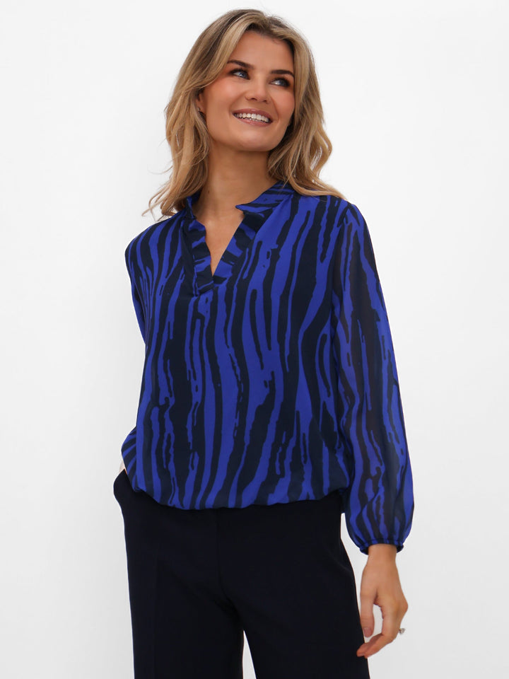 Woman wearing a blue zebra print blouse against a white background