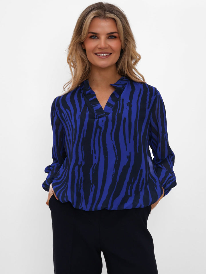 Woman wearing a blue zebra pattern blouse against a white background