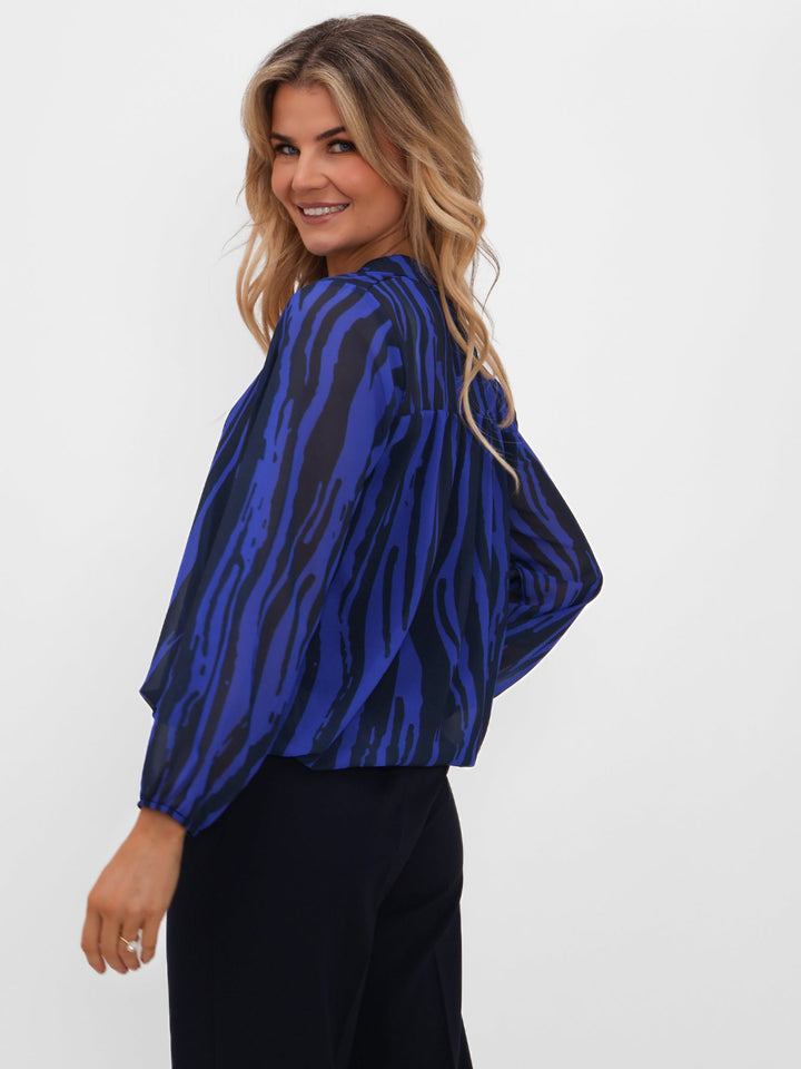 Woman wearing a blue and black patterned top against a white background