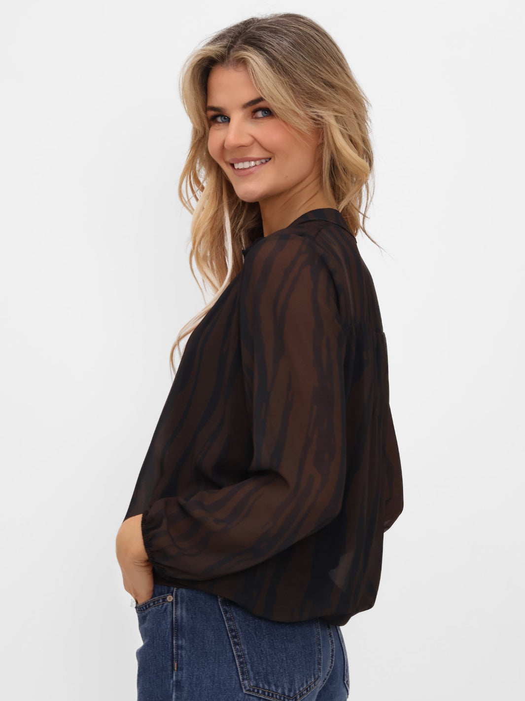 Woman wearing a sheer black blouse and blue jeans on a white background