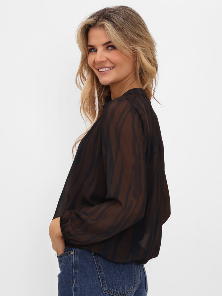 Woman wearing a sheer black blouse and blue jeans on a white background