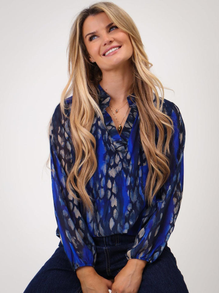 Woman wearing a blue patterned blouse against a white background