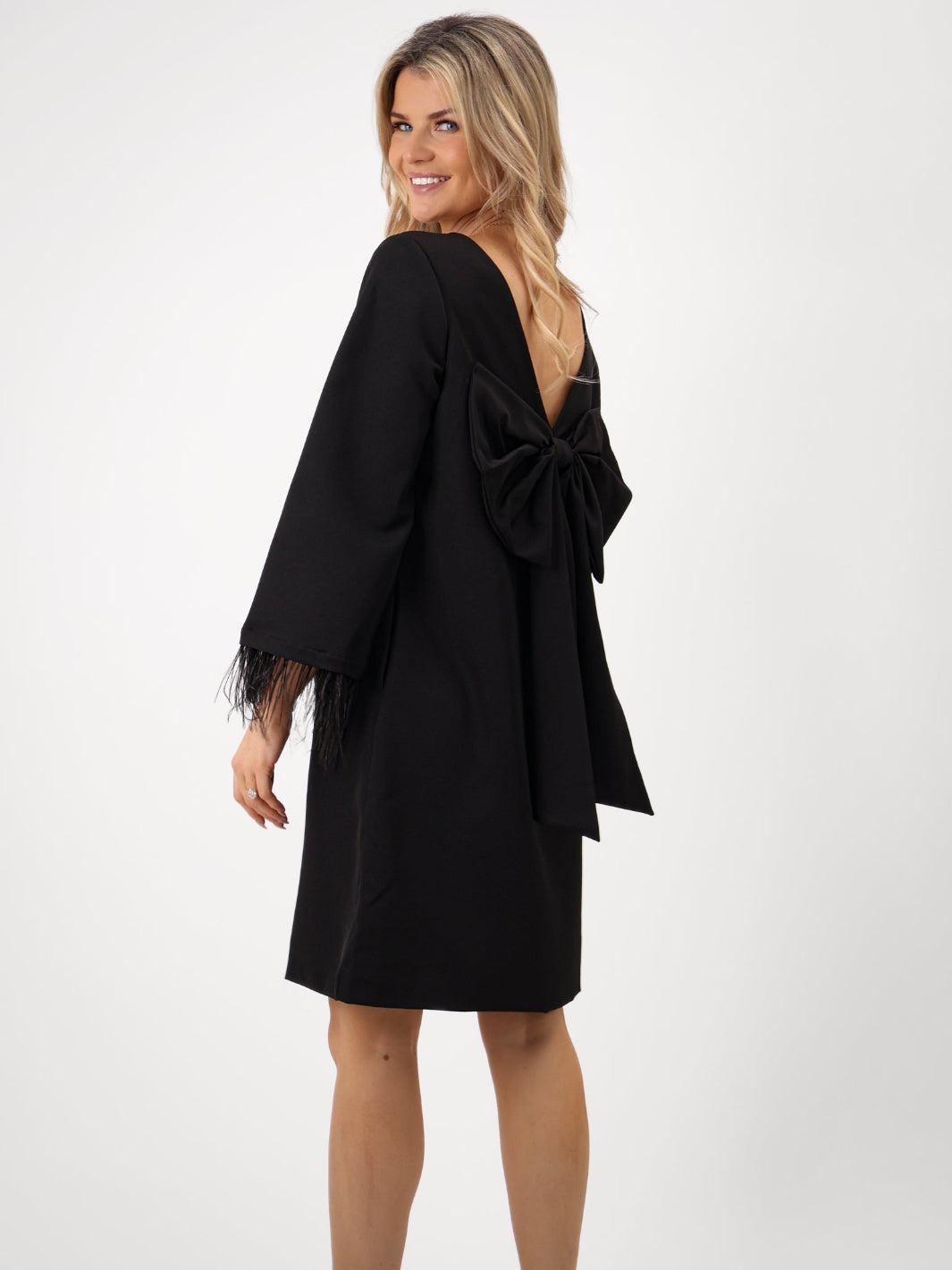 Woman wearing a black dress with ruffled sleeves on a white background