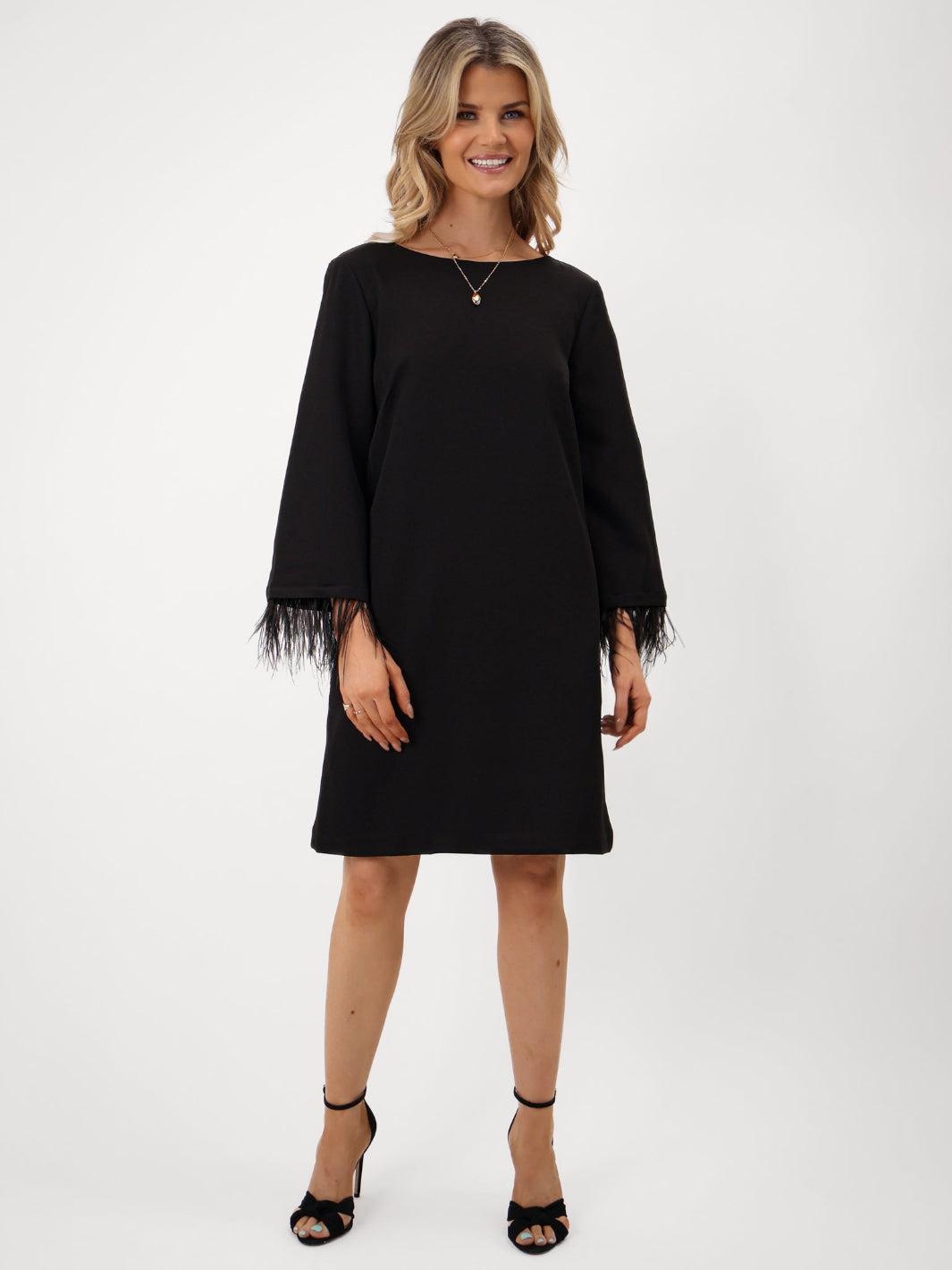 Woman wearing a black dress with sheer sleeves on a white background