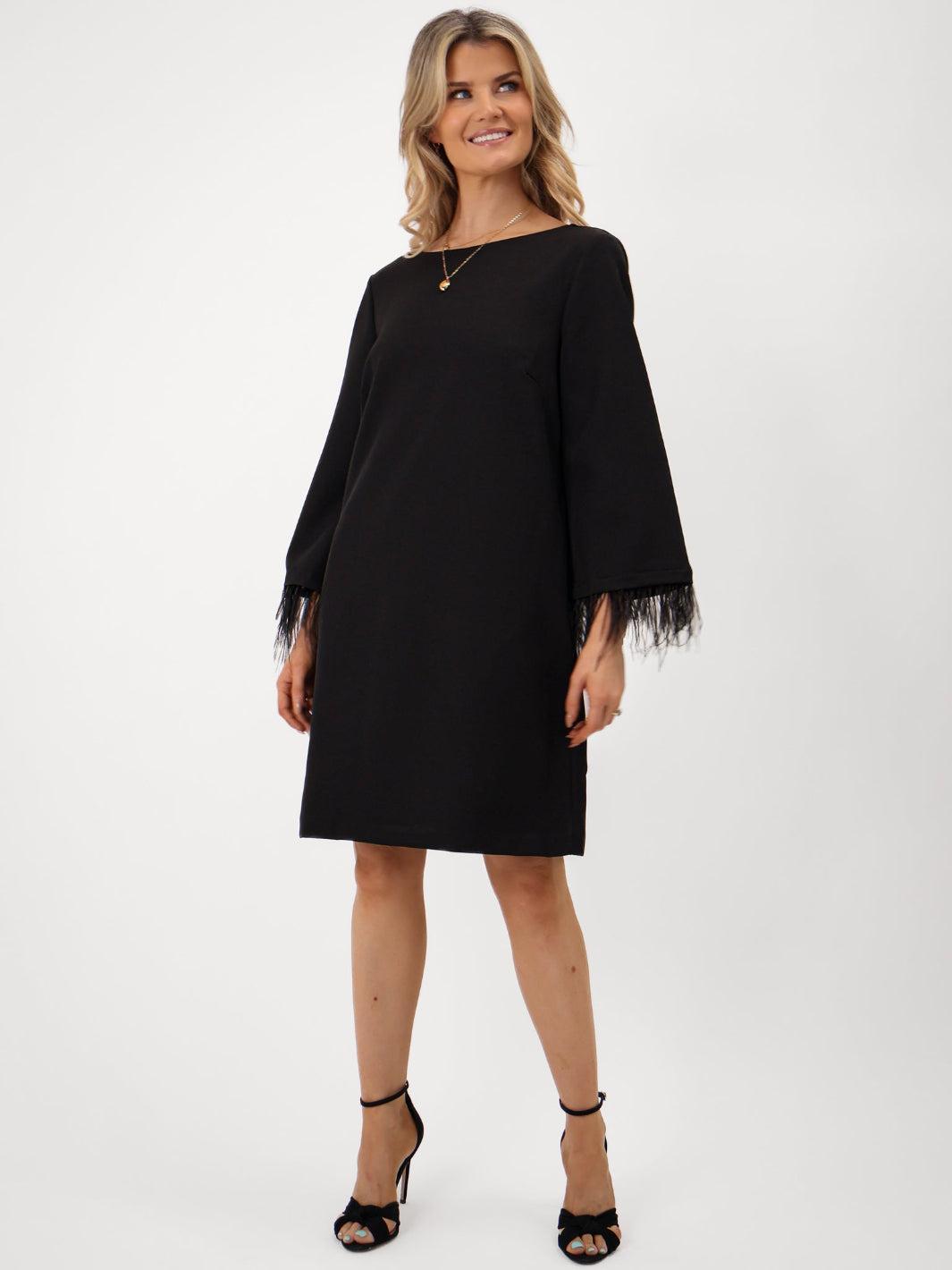 Woman wearing a black dress with fringe sleeves on a white background