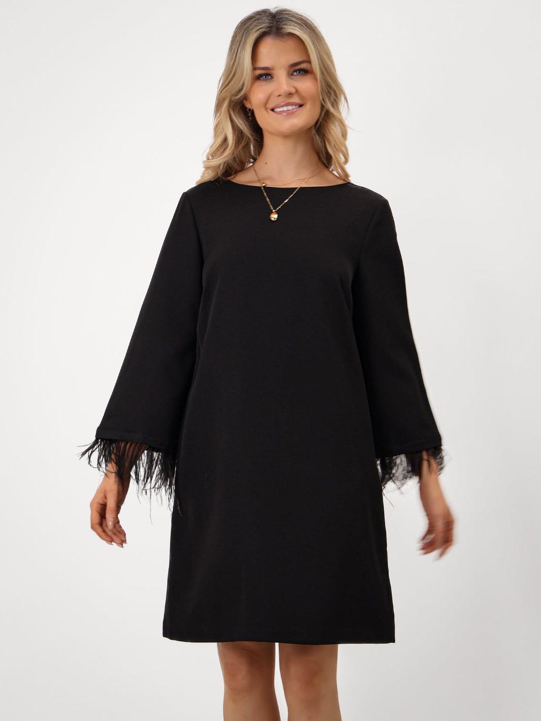 Woman wearing a black dress with lace cuffs on a white background