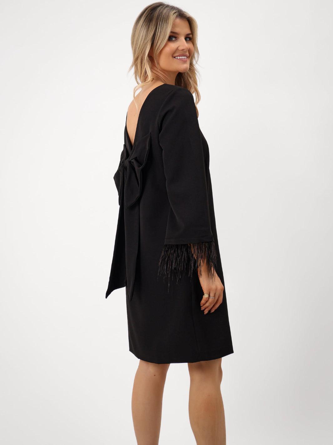 Woman wearing a black dress with a bow detail on a white background