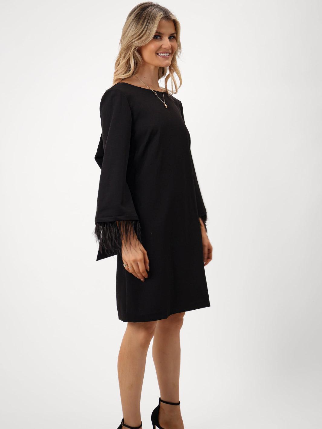 Woman wearing a black dress with sheer sleeves on a white background