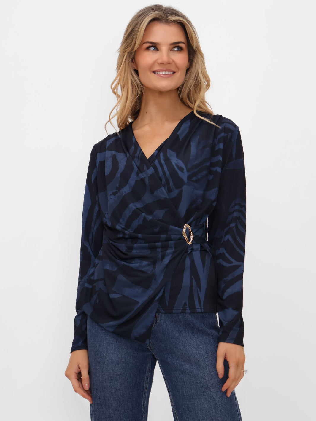 Woman wearing a navy patterned top with a belt against a white background