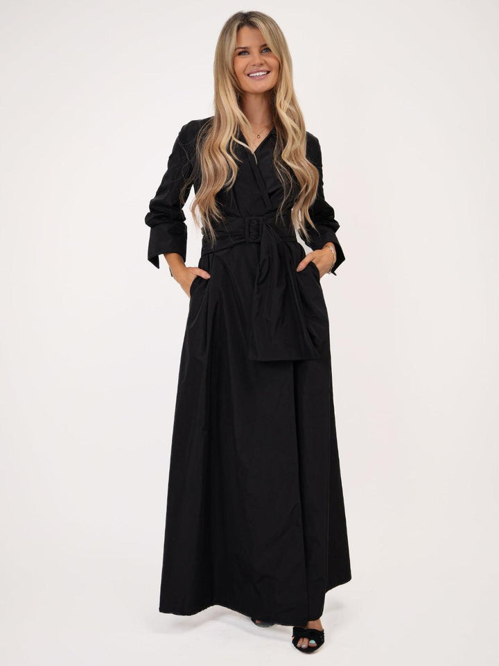Woman wearing a black outfit with a belt on a white background