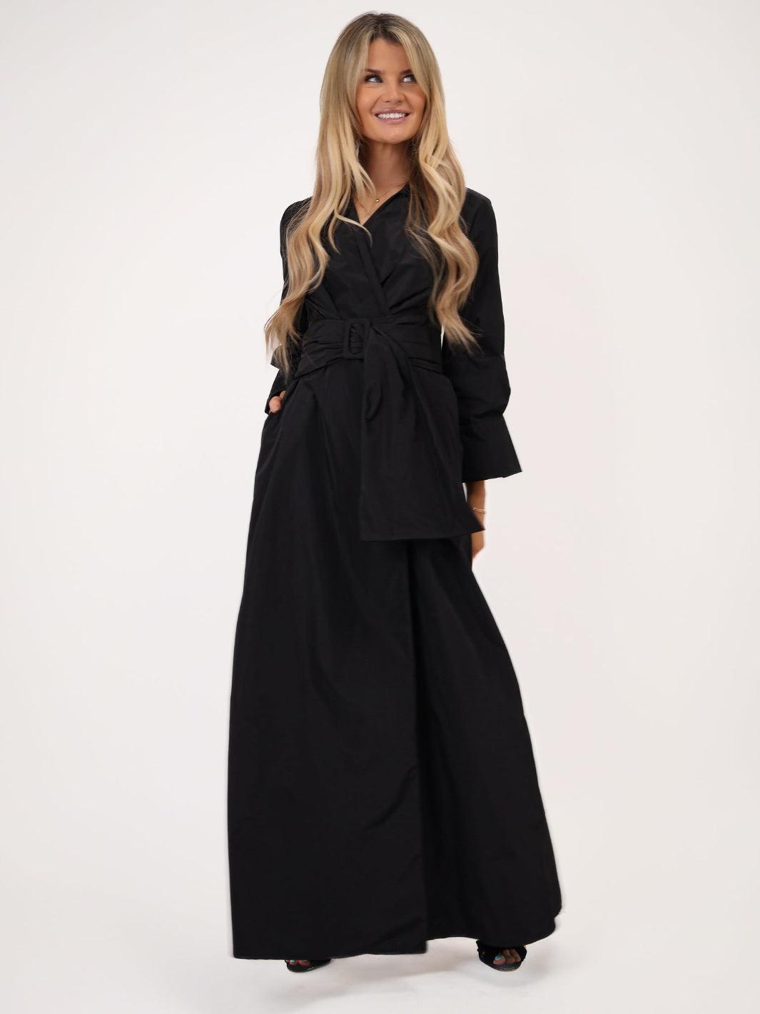Woman wearing a black outfit with a belt on a white background