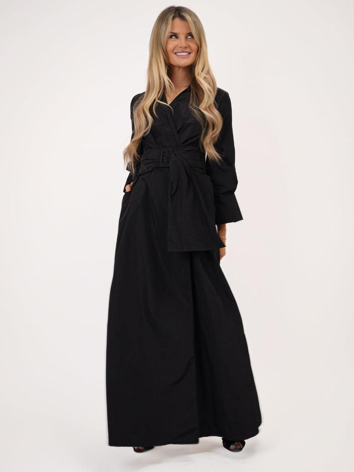 Woman wearing a black outfit with a belt on a white background