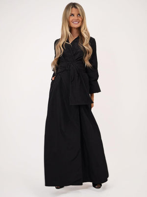 Woman wearing a black outfit with a belt on a white background