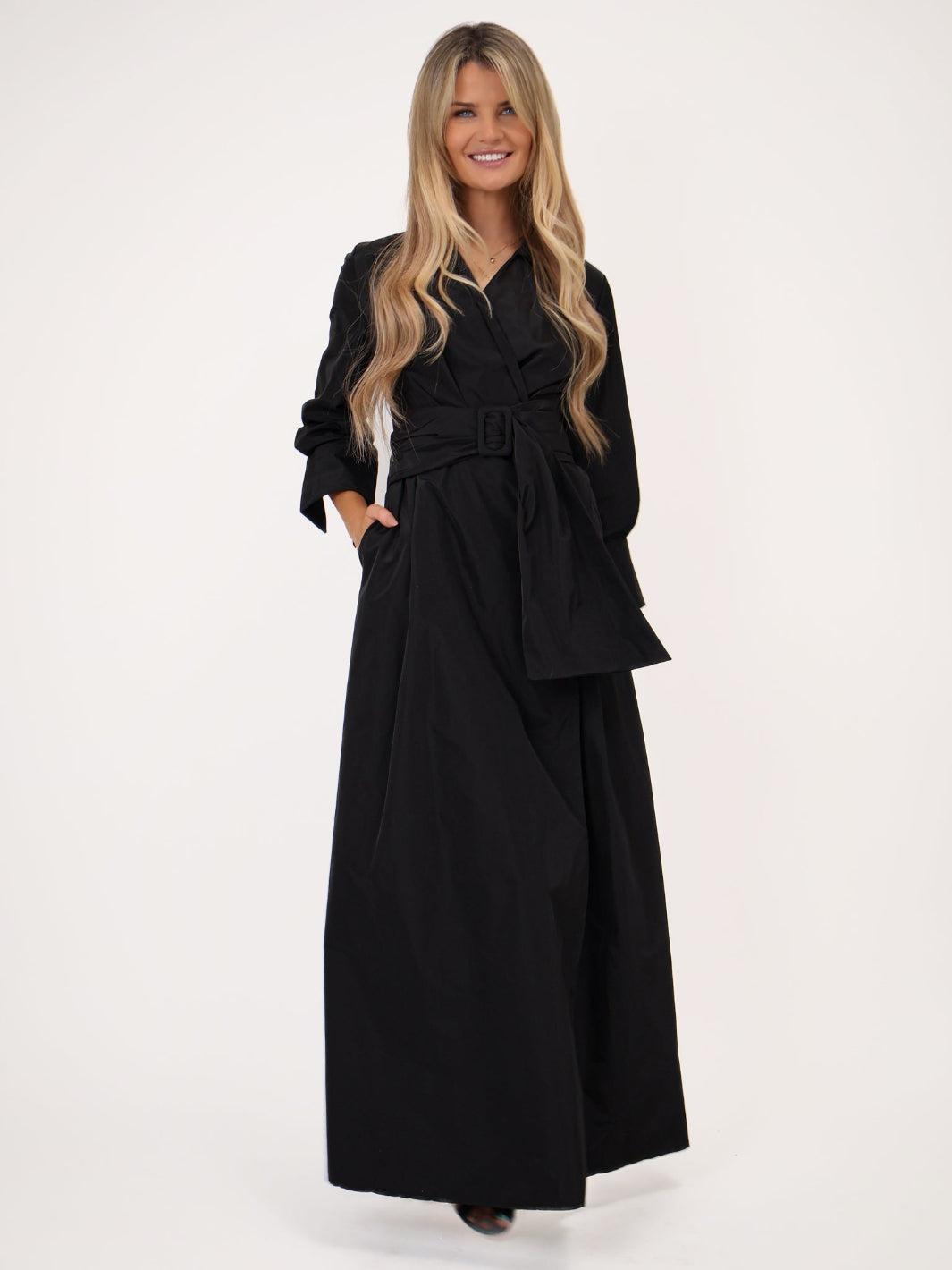 Woman wearing a black dress with a belt on a white background
