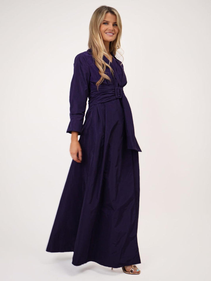 Woman wearing a long dark purple dress on a white background