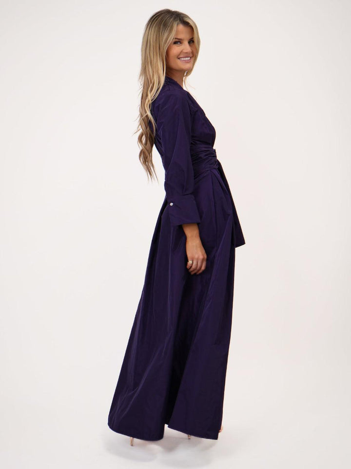 Woman wearing a long dark purple dress on a white background