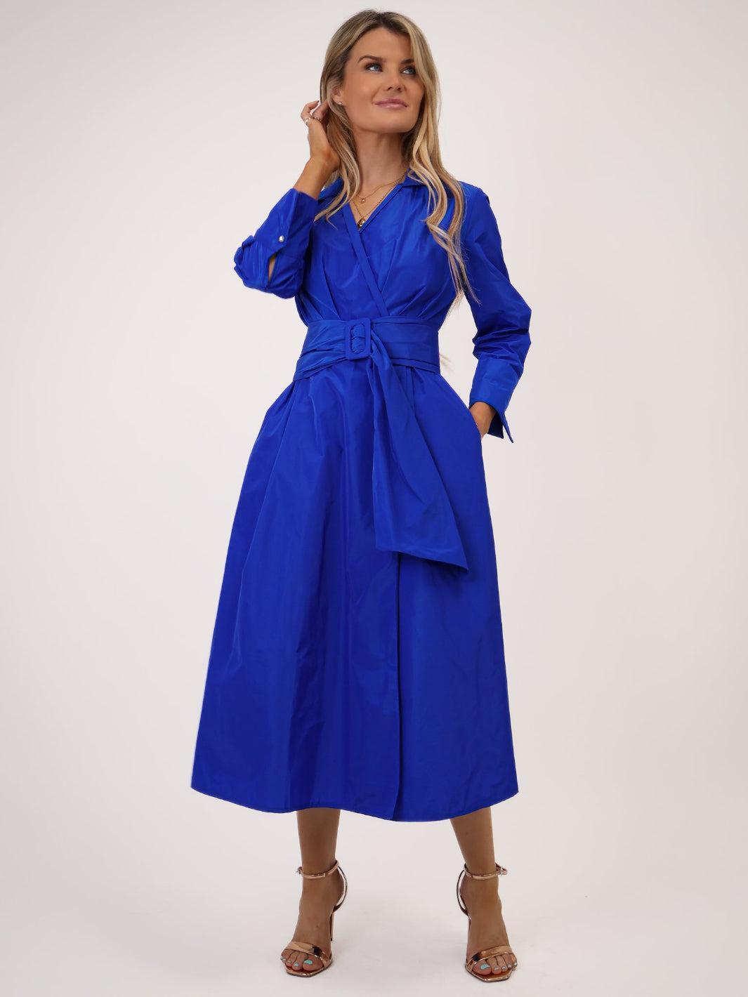 Woman wearing a blue dress with a belt on a white background
