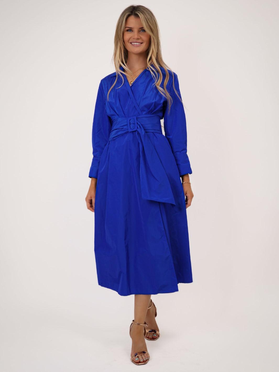 Woman wearing a blue dress with a belt on a white background