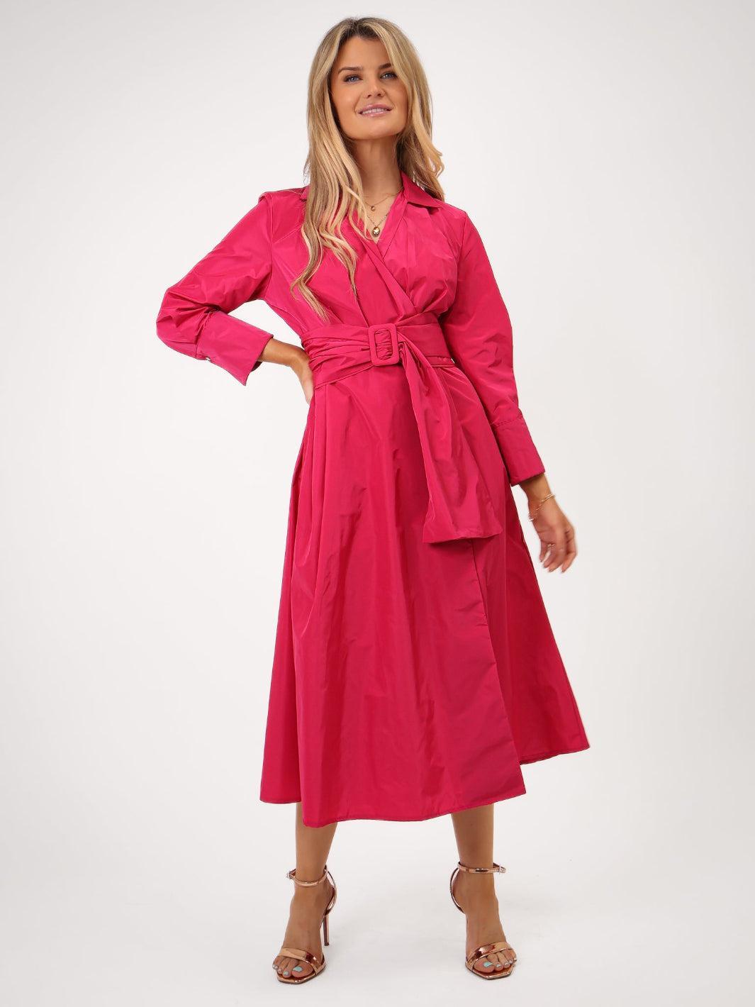 Woman wearing a bright pink dress with a belt on a white background