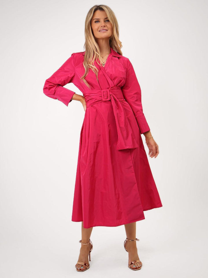 Woman wearing a bright pink dress with a belt on a white background