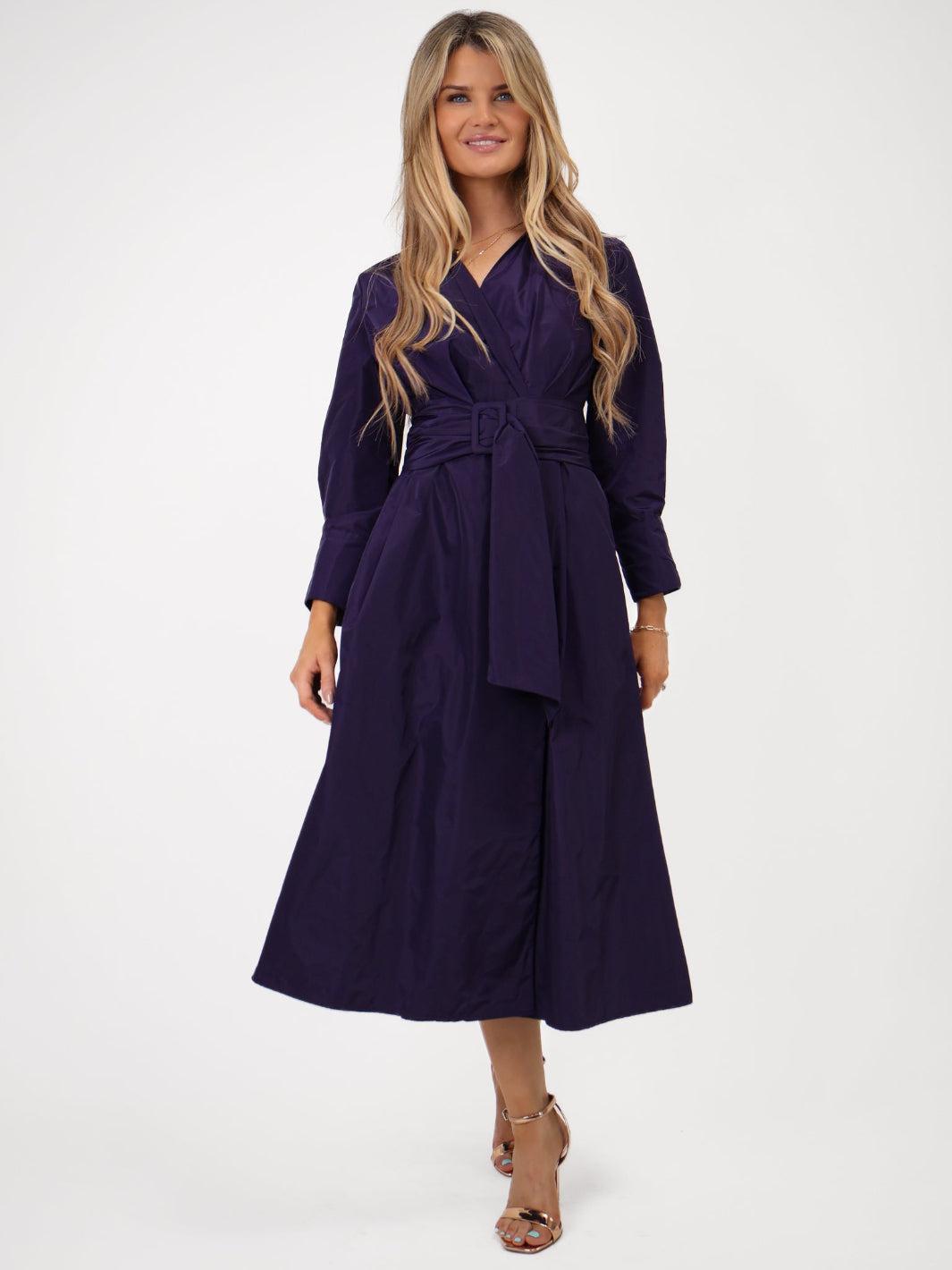 Woman wearing a purple dress with a belt on a white background