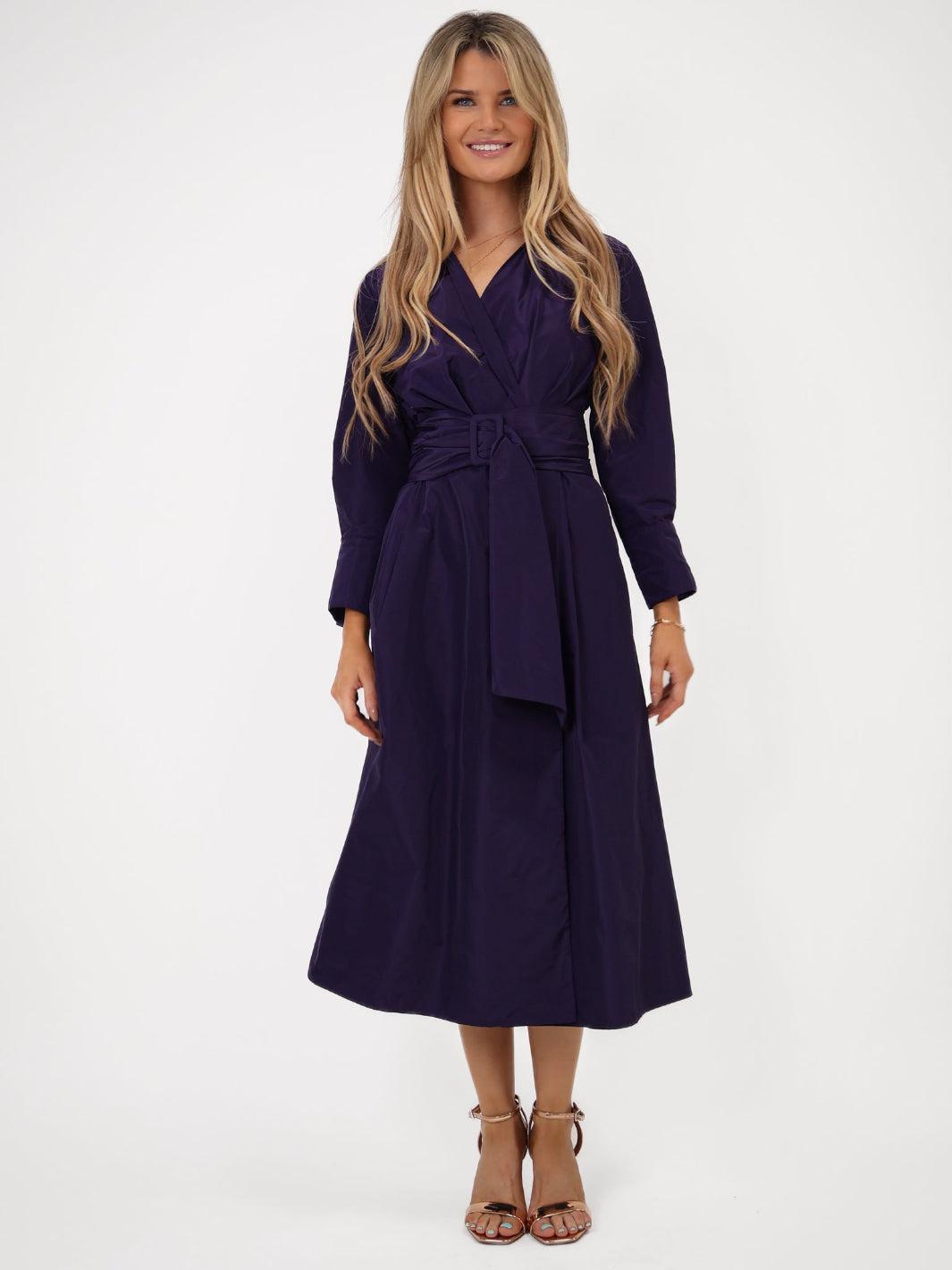 Woman wearing a purple dress with a belt on a white background