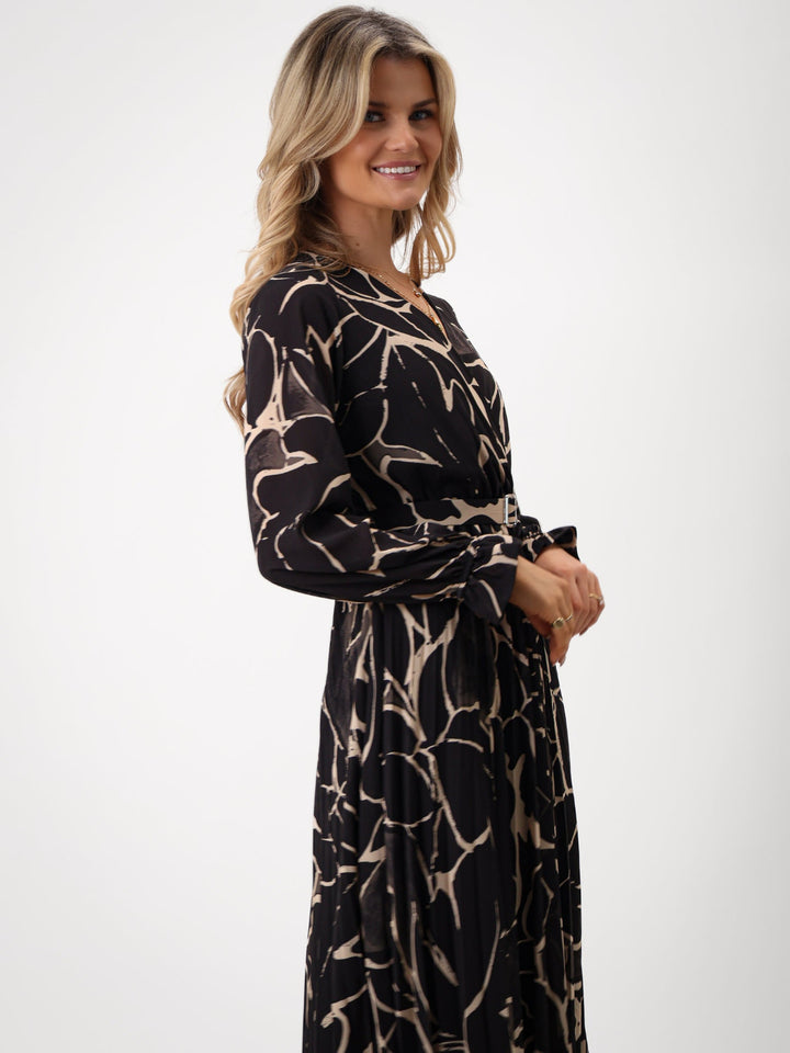 Woman wearing a black and beige patterned dress on a white background