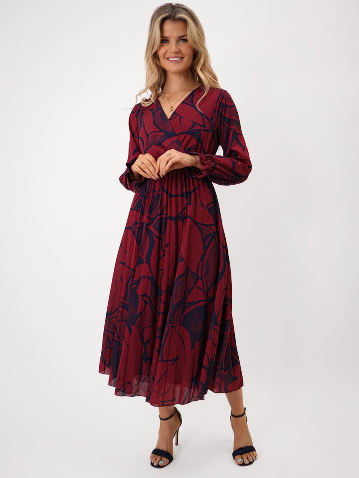 Woman wearing a red and navy patterned dress on a white background