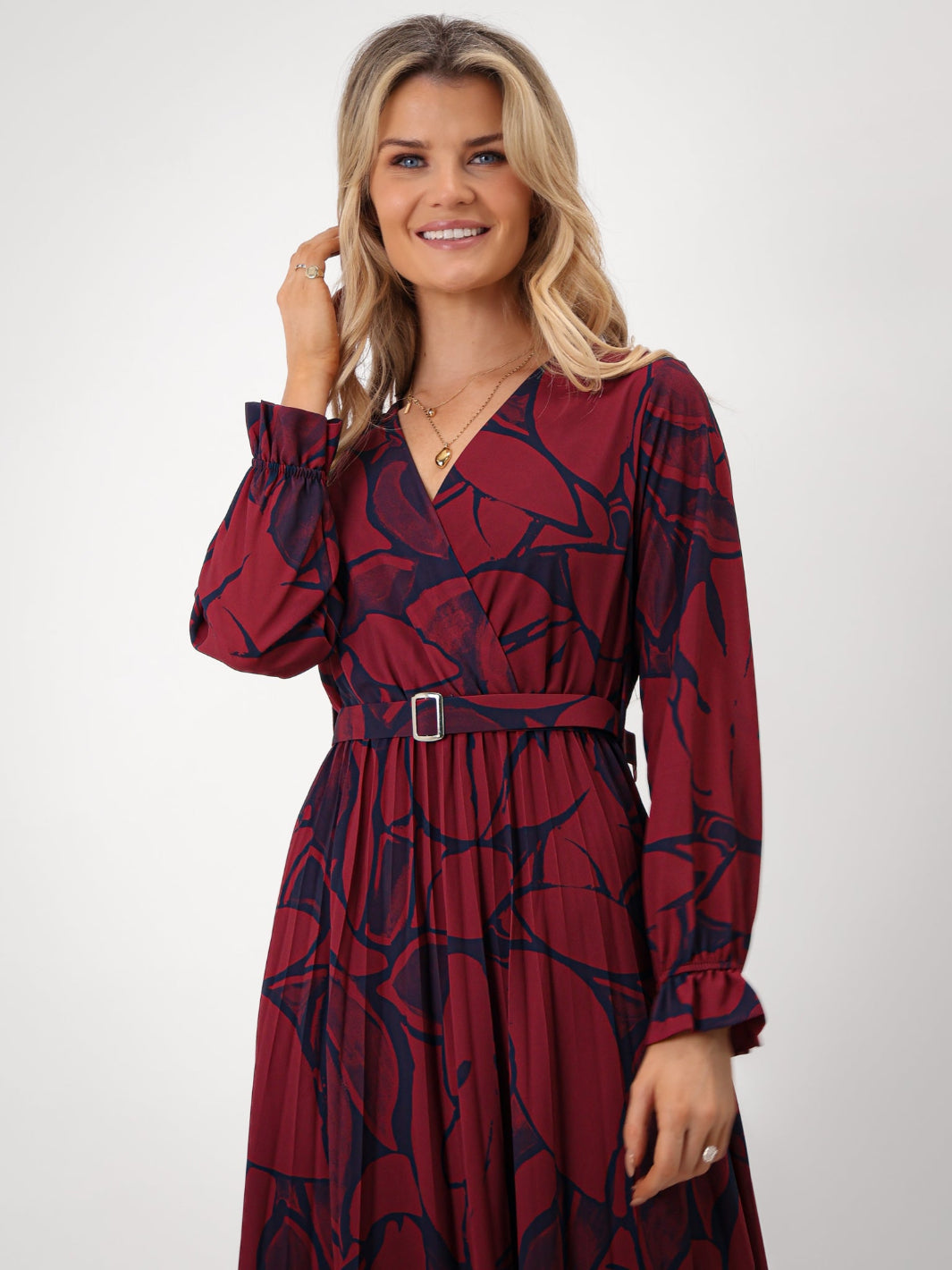 Woman wearing a red and navy patterned dress on a white background