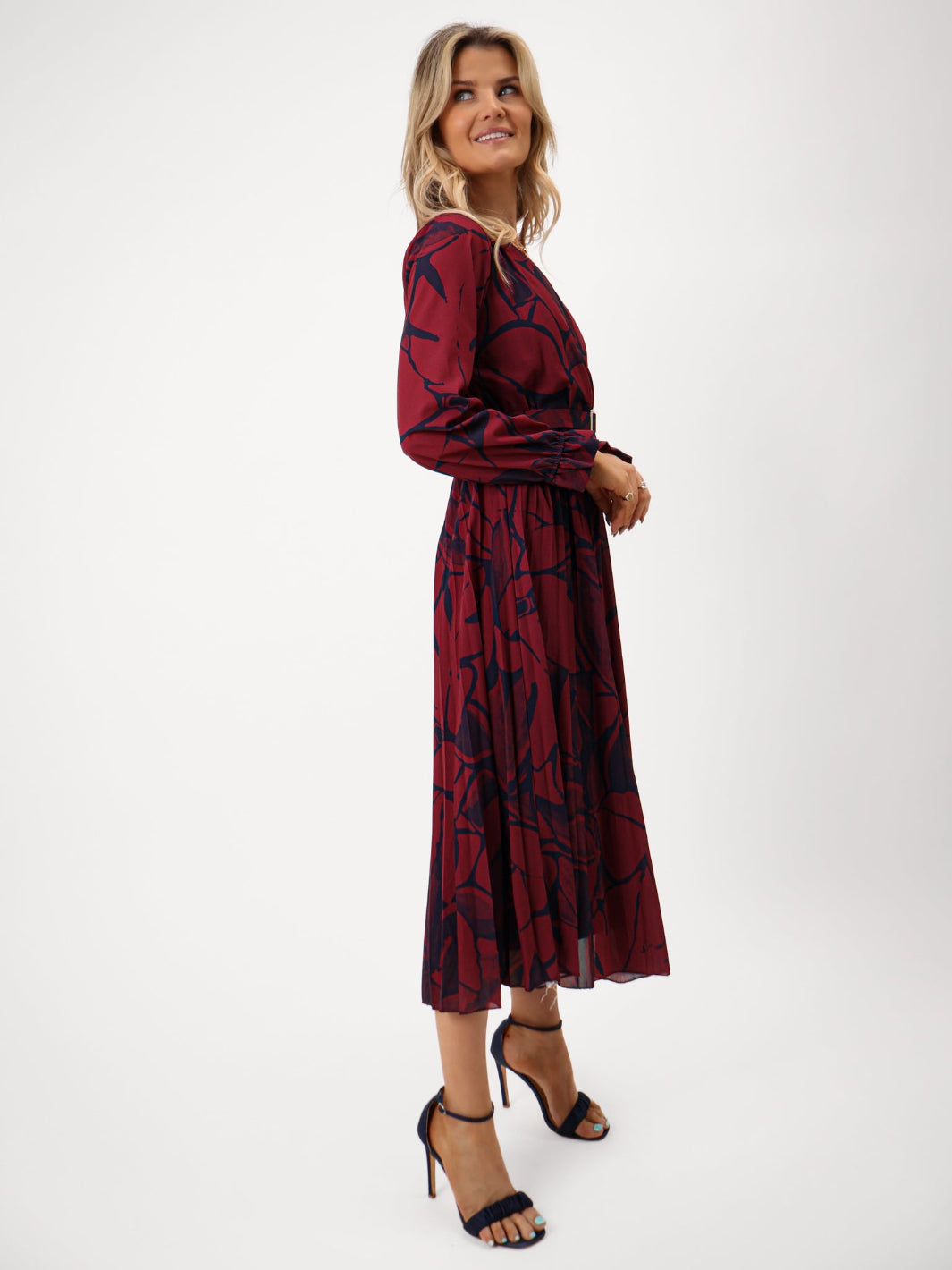 Woman wearing a burgundy dress with black abstract pattern on a white background