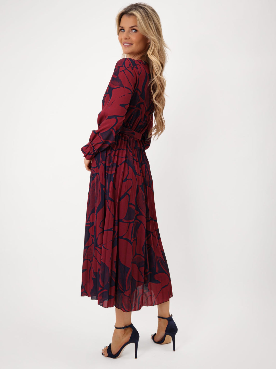 Woman wearing a burgundy dress with black floral pattern on a white background