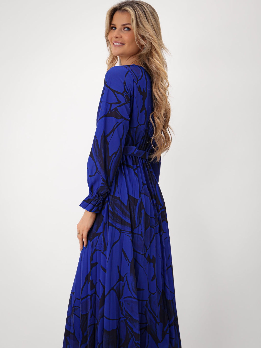 Woman wearing a blue dress with black abstract patterns on a white background