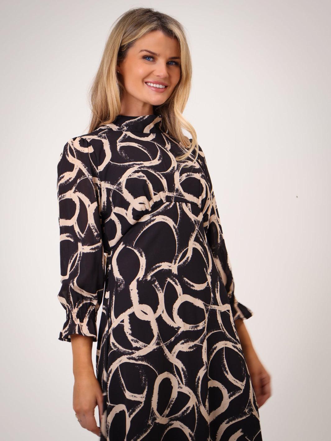 Woman wearing a black and beige patterned dress on a white background