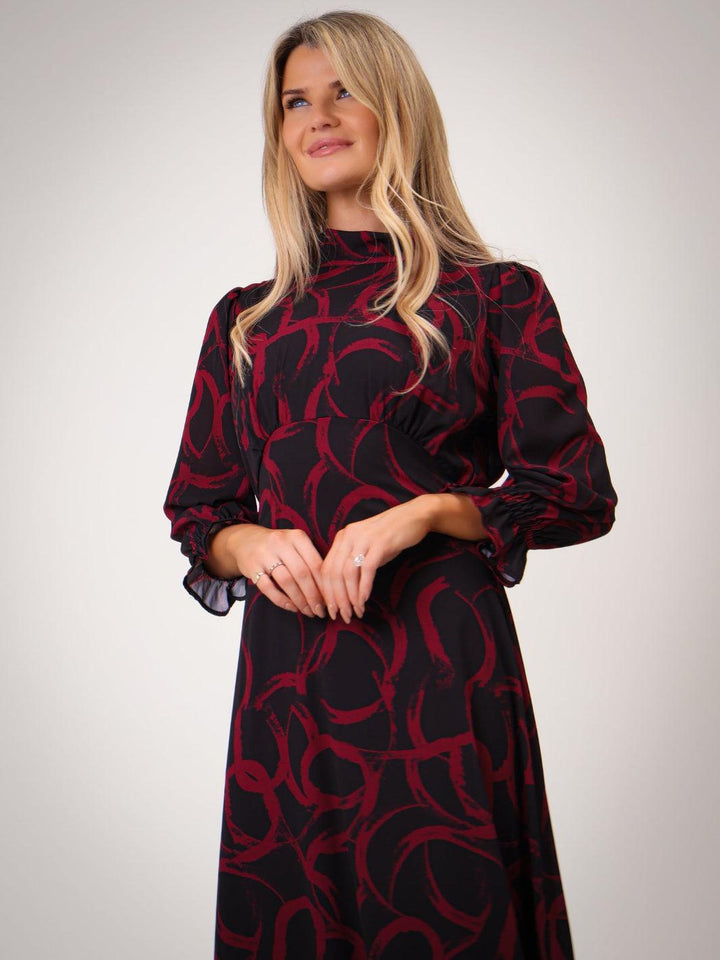 Woman wearing a black dress with red pattern against a white background