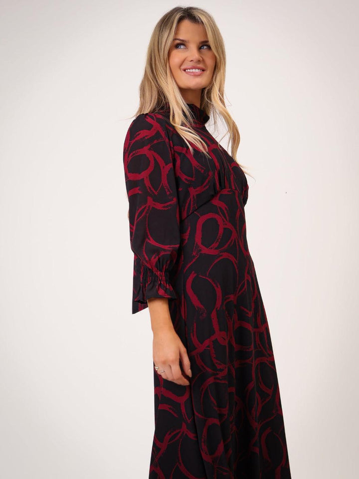 Woman wearing a black dress with red pattern on a white background