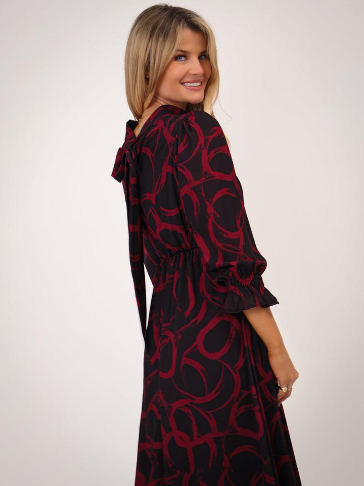 Woman wearing a black and red patterned dress on a white background