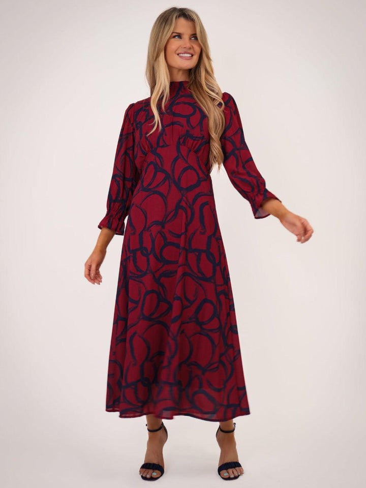 Woman wearing a red dress with black pattern on a white background