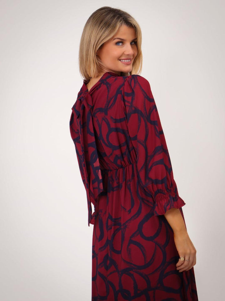 Woman wearing a red dress with a black pattern on a white background