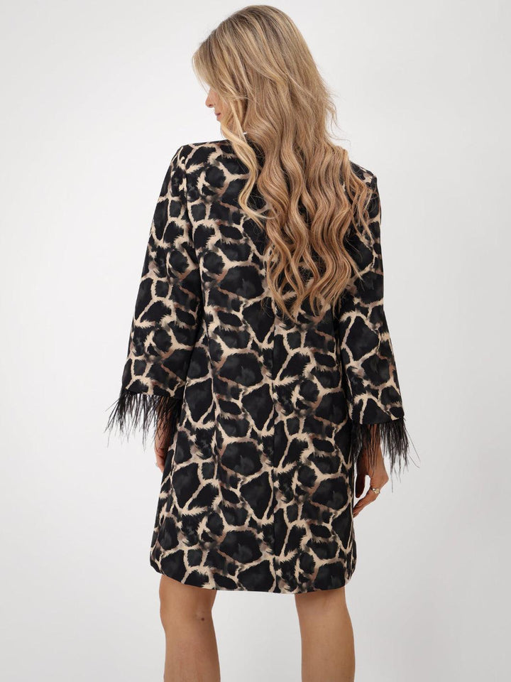 Person wearing a leopard print dress with fringes on a white background