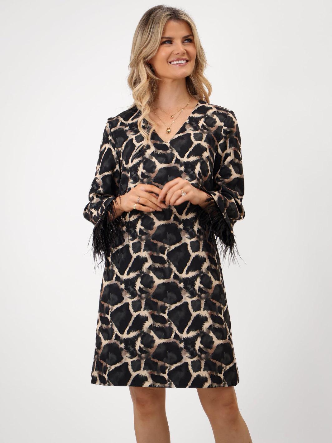 Woman wearing a leopard print dress with feather details on a white background