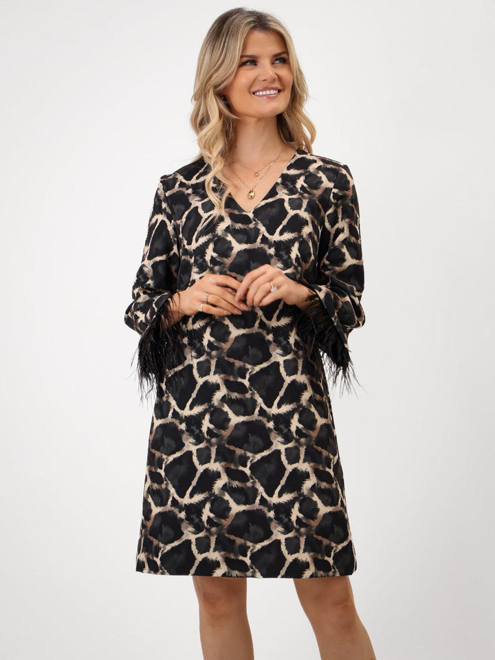 Woman wearing a leopard print dress with feather details on a white background