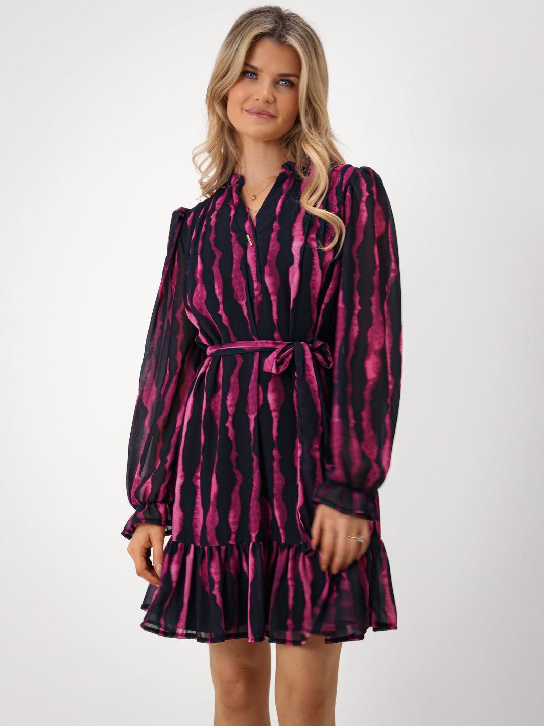 Woman wearing a black and pink patterned dress on a white background
