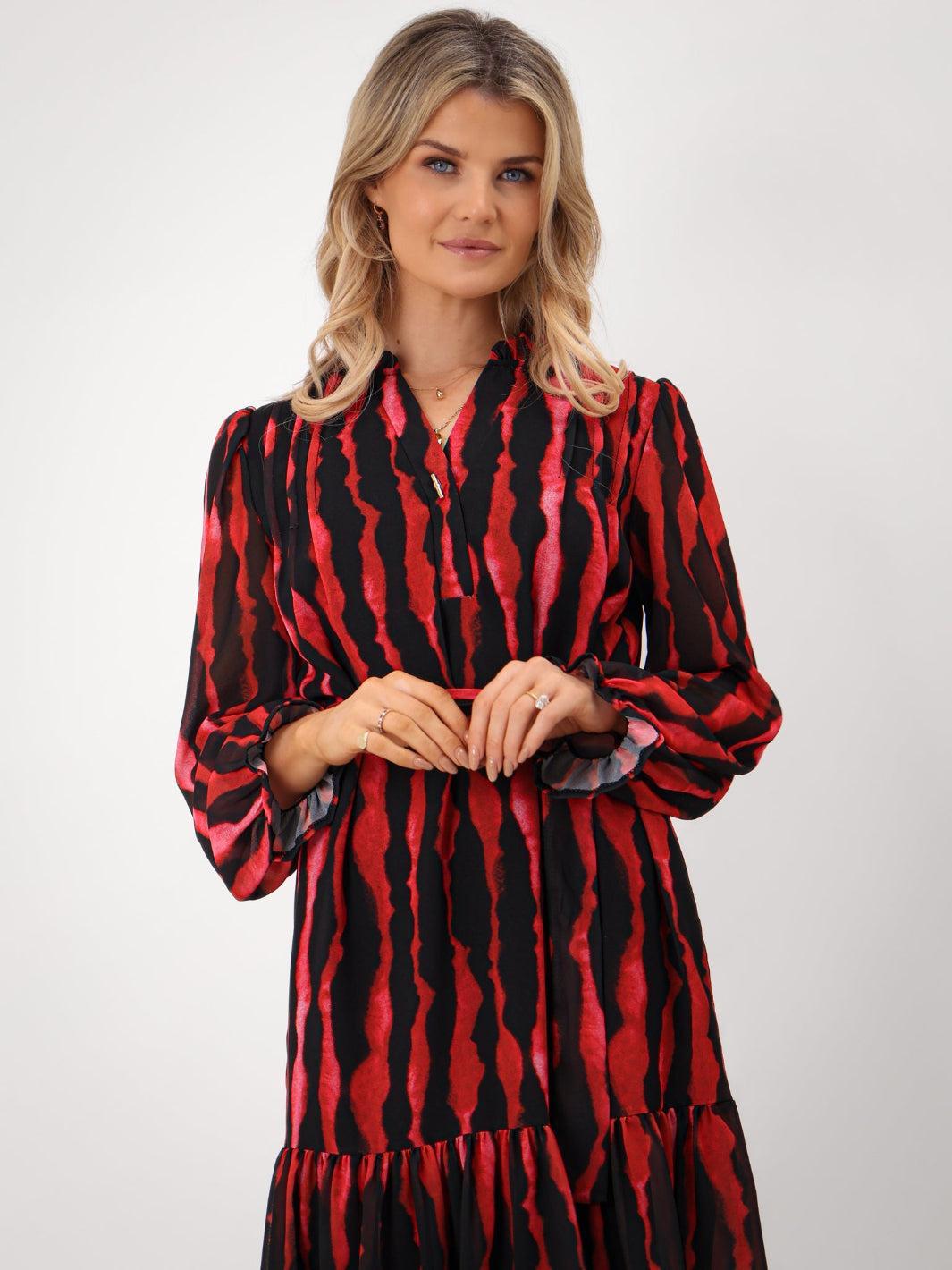 Woman wearing a red and black patterned dress on a white background