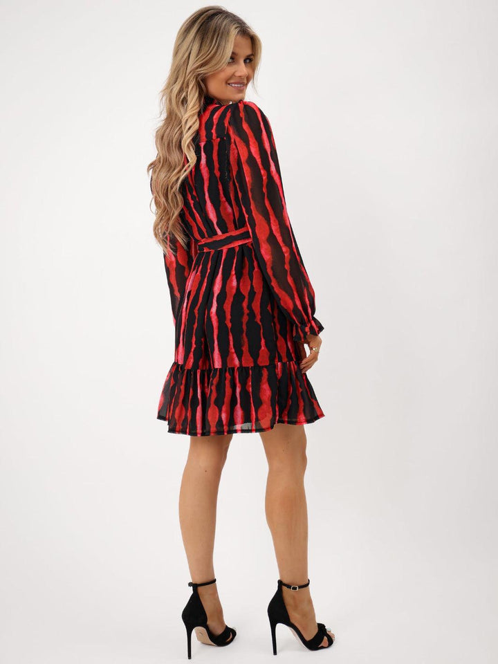 Woman wearing a red and black patterned dress on a white background