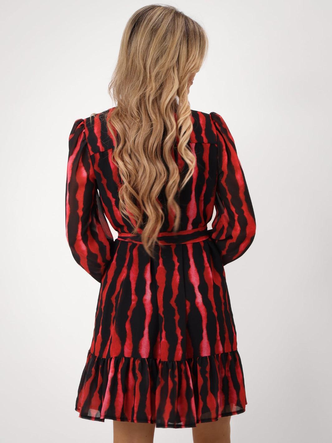 Red and black patterned dress worn by a person on a white background
