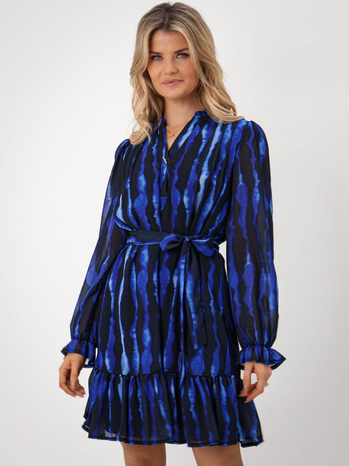 Woman wearing a blue and black patterned dress on a white background