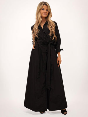 Woman wearing a black long dress with a belt on a white background