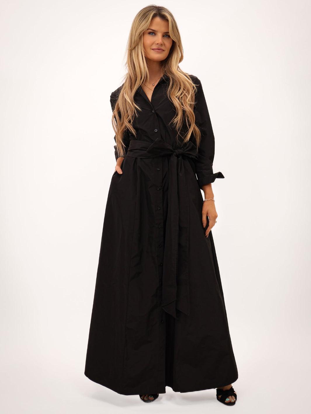 Woman wearing a black long dress with a belt on a white background
