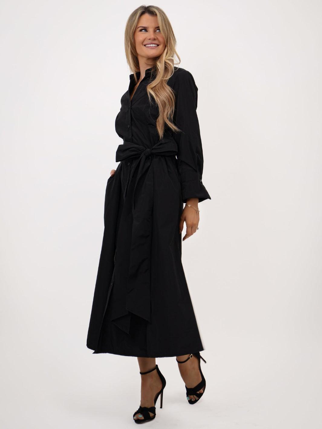 Woman wearing a black dress with a belt on a white background
